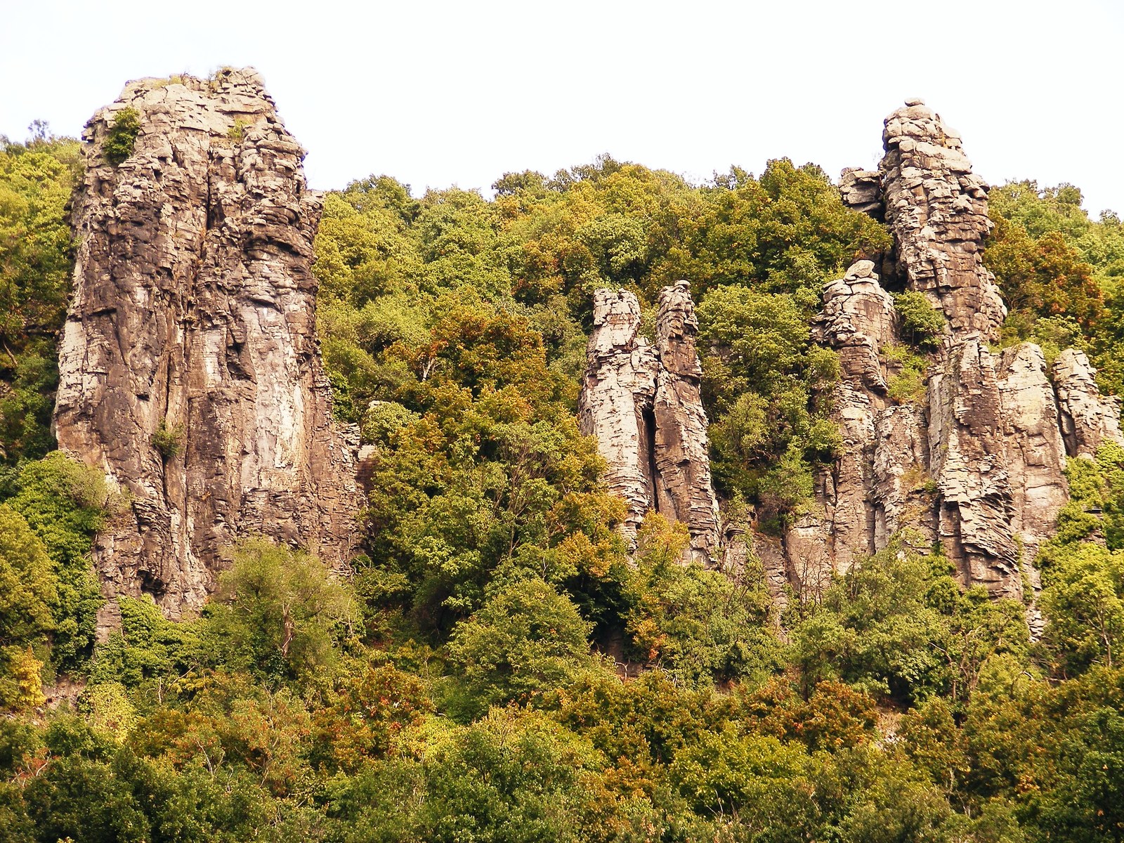Tall columns of weathered rock rise above a wooded slope.